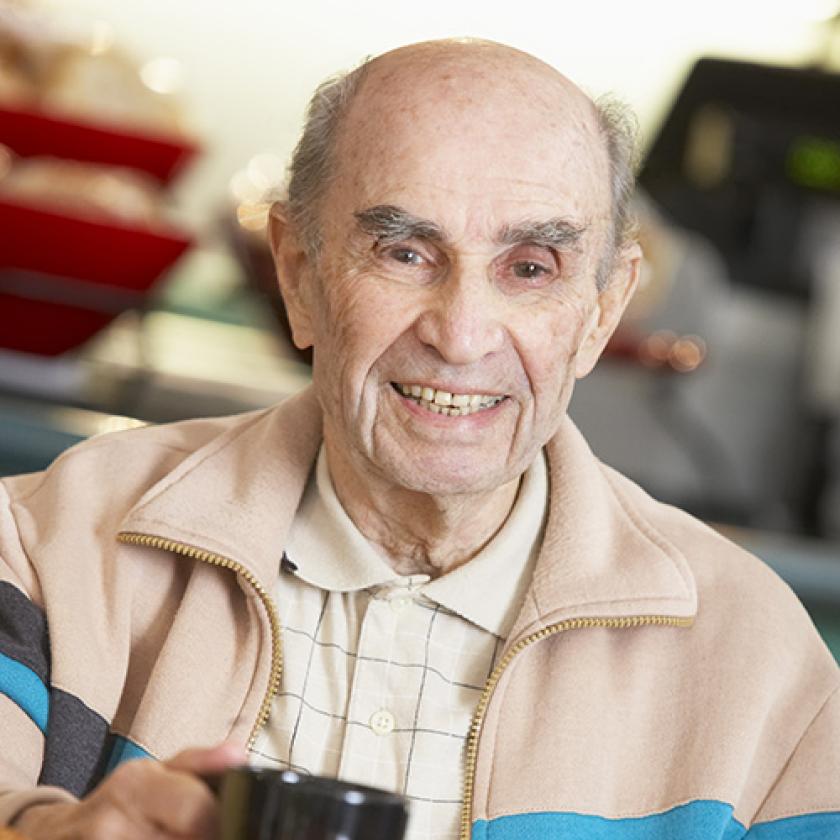 Senior man smiling as he drinks a cup of coffee